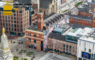 Aerial view of The Electric Press in Leeds city centre, featuring the restored red-brick Grade II listed building with large colourful mural artwork along the side elevation. The image includes Millennium Square in the foreground and surrounding historic and contemporary buildings. A “BCO Regional Awards Shortlisted 2026” graphic appears in the top left corner.