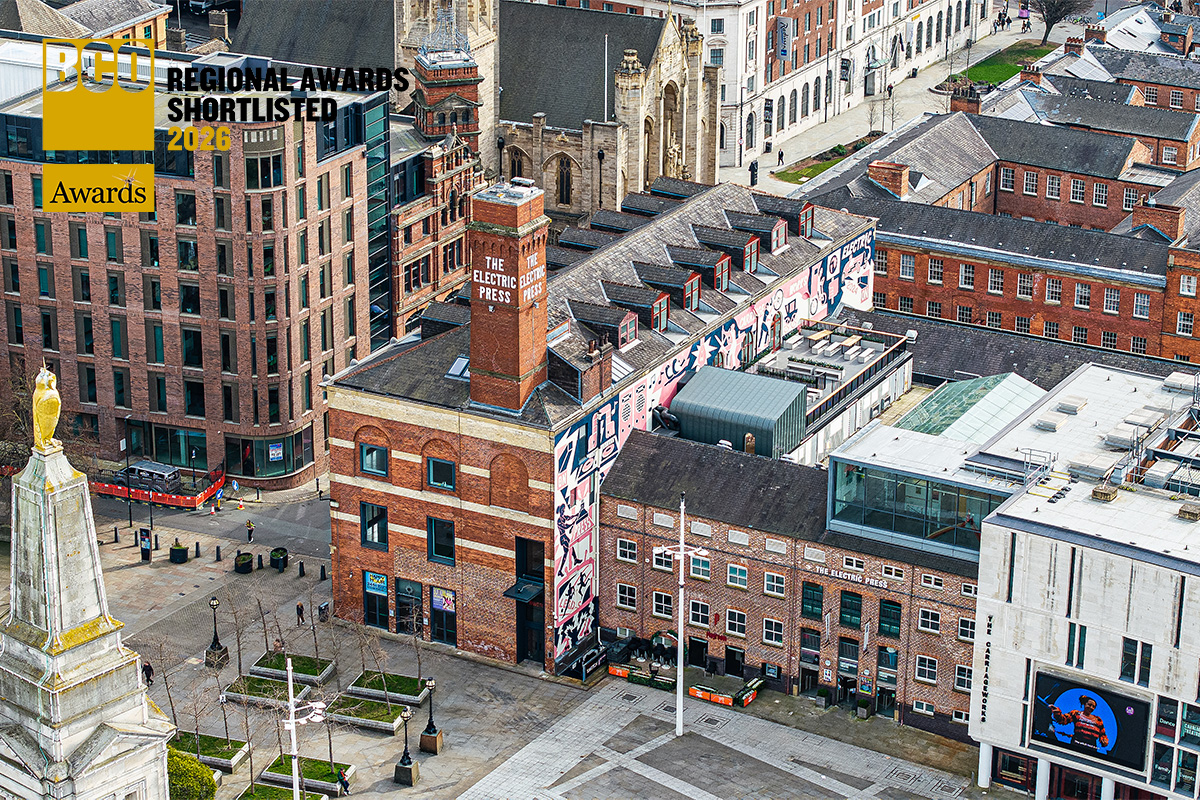 Aerial view of The Electric Press in Leeds city centre, featuring the restored red-brick Grade II listed building with large colourful mural artwork along the side elevation. The image includes Millennium Square in the foreground and surrounding historic and contemporary buildings. A “BCO Regional Awards Shortlisted 2026” graphic appears in the top left corner.